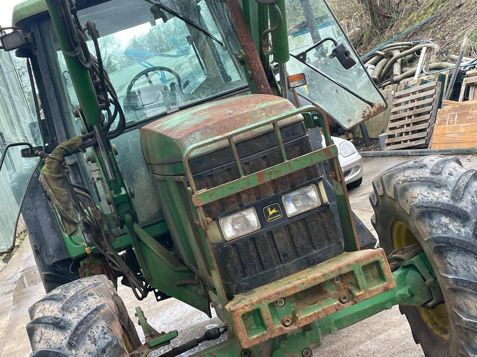 John Deere tractor with loader before, with faded, rusty paintwork